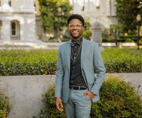 Man in blue suit smiles for a photo